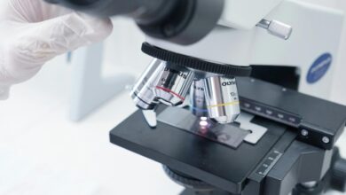 Seseorang dengan sarung tangan putih sedang melihat melalui mikroskop