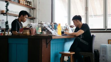 Pria berbaju kaos leher kru hitam duduk di kursi kayu coklat