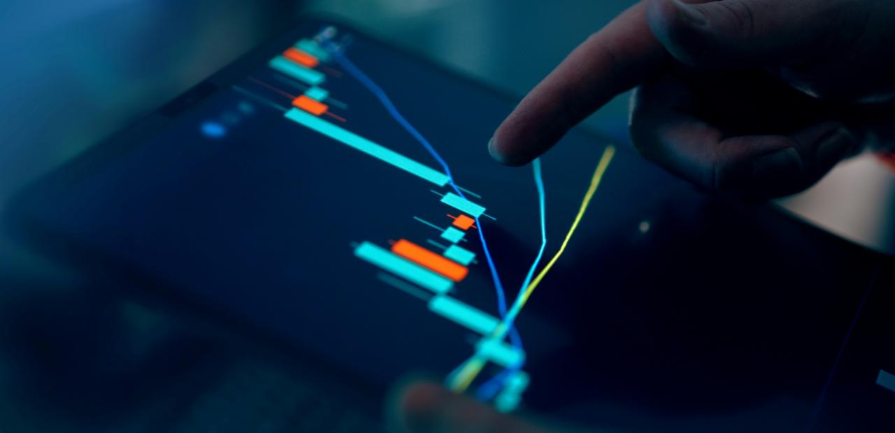 Jari berinteraksi dengan grafik pasar saham pada tablet.